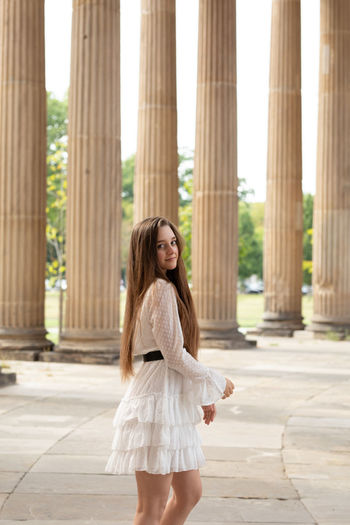 Portrait of young woman standing against columns