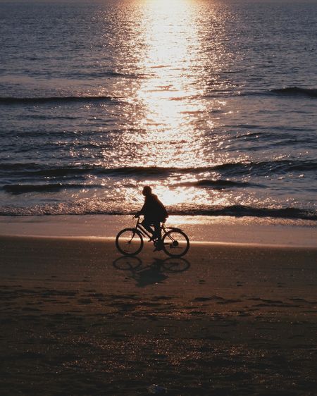Teenager boy cycling on beach