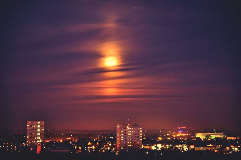 Illuminated cityscape against sky at night