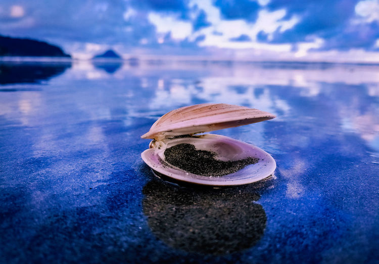 Close-up of ice cream on sand against lake