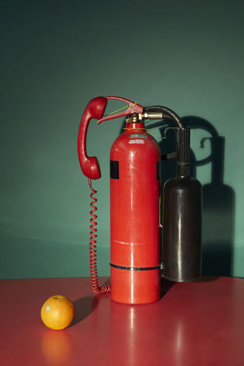 Close-up of fire extinguisher on table against wall