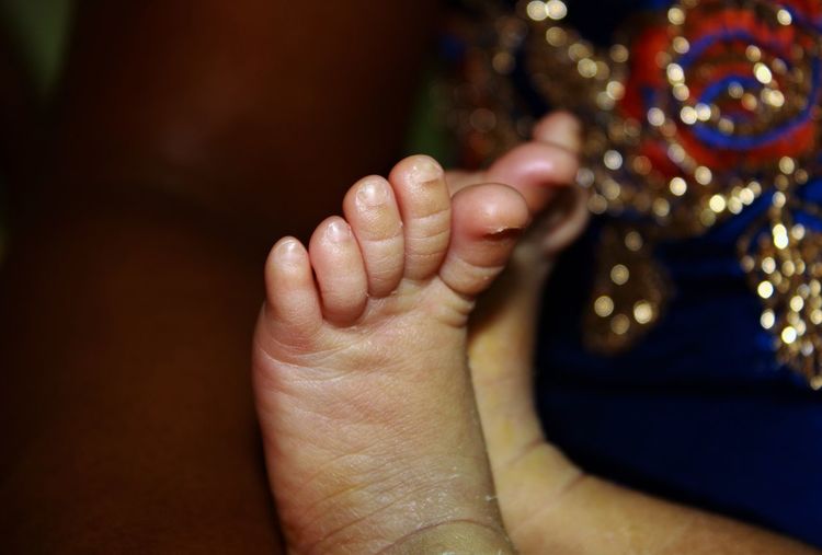Close-up of baby barefoot against sky at night