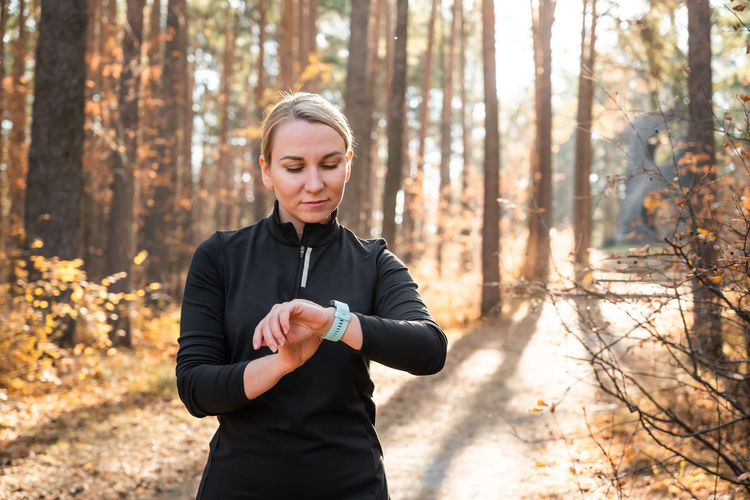 Girl checking smart watch with fitness tracker, looking at health data while exercising