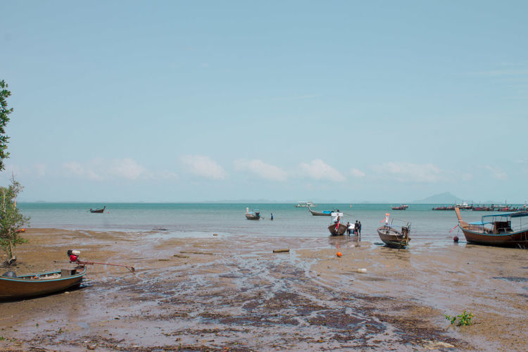 Boats moored on beach against sky