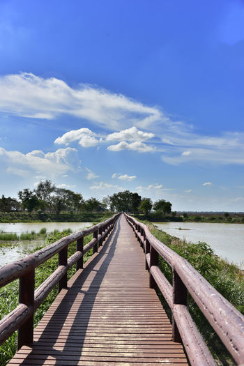 View of wooden bridge over calm sea against sky