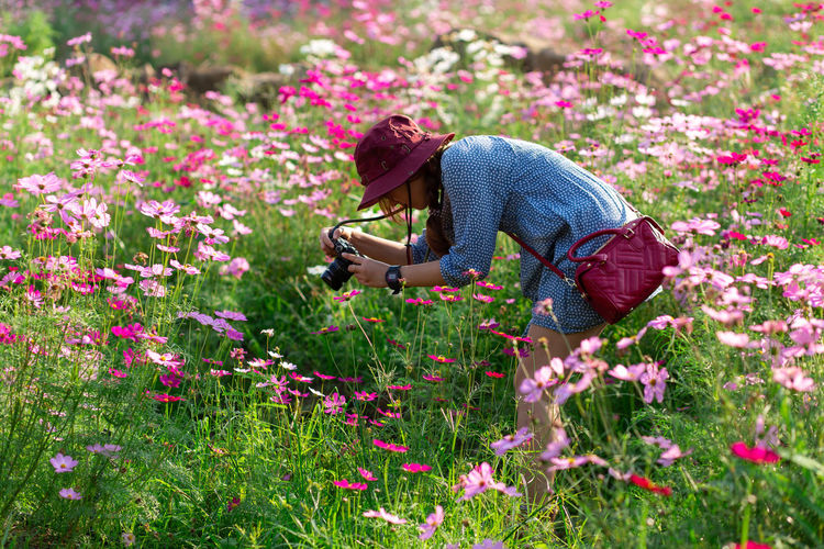 Side view of person on flowering plants on field