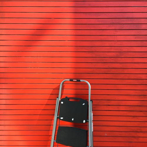 View of ladder next to red wall