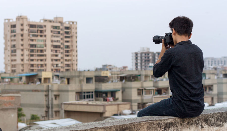 Man photographing with cityscape in background
