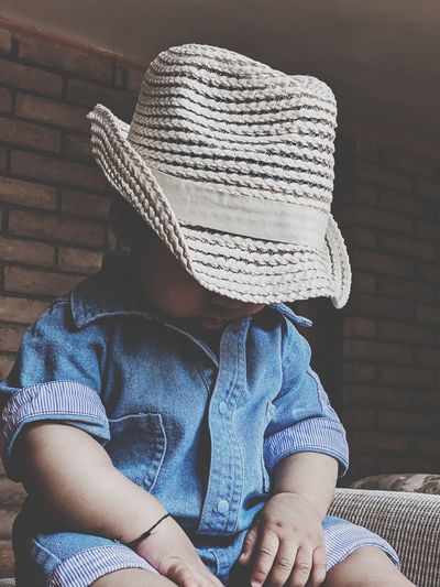 Rear view of boy sitting on seat with a hat on