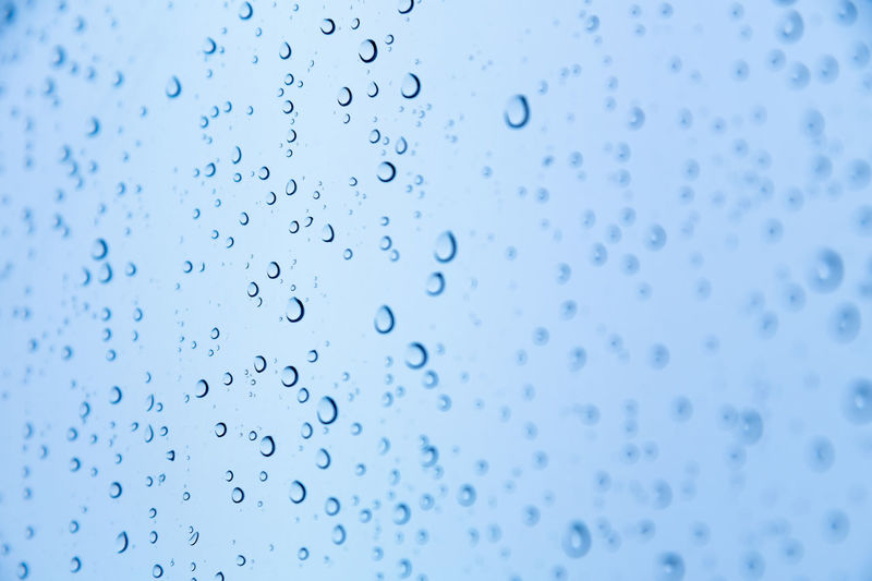 Close-up of raindrops or snow drops on a blue windowpane. freshness background 