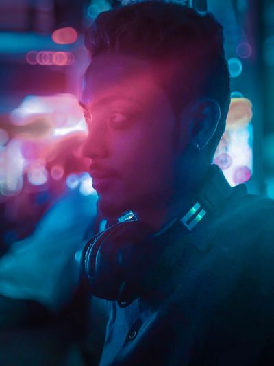 Close-up of thoughtful man with headphones in nightclub