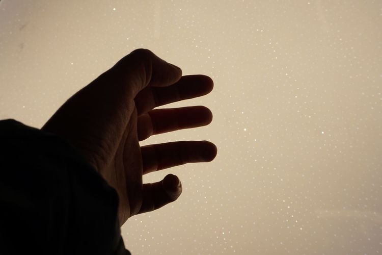 Cropped hand against star field at night