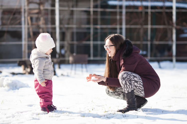 Mother playing with daughter in snow