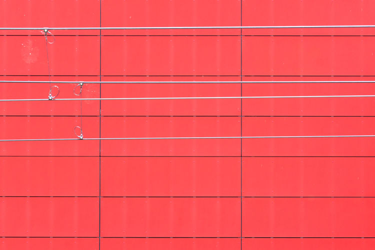 Full frame shot of red wall with electric cable 