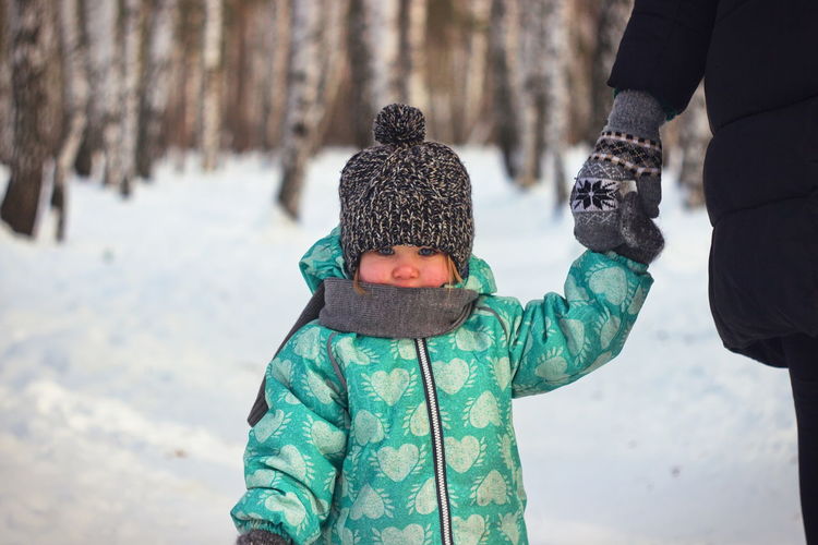 Cropped hand of person holding baby during winter