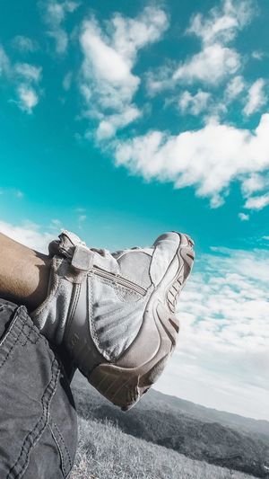 Low section of person relaxing against sky