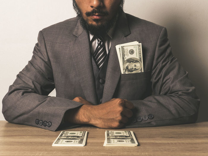 Midsection of businessman with paper currency at table