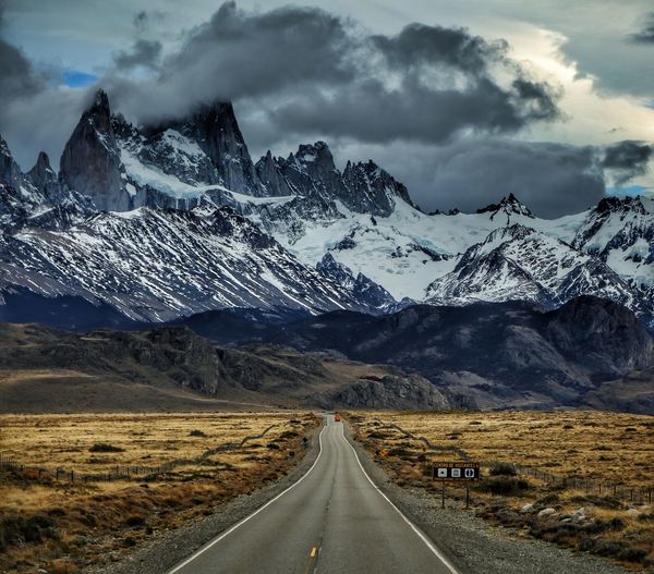 Scenic view of road against snowcapped mountains