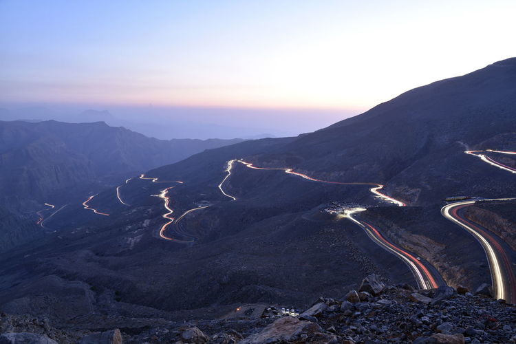 View of light trails on mountain road during dusk
