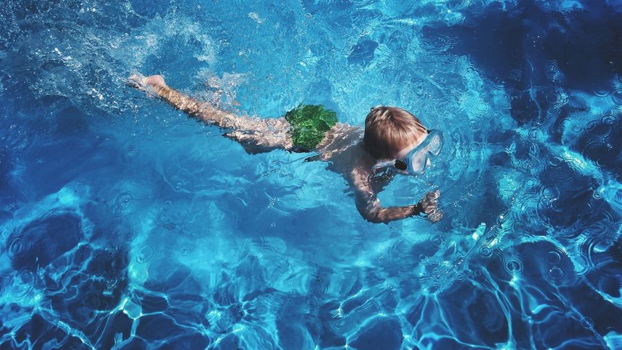 High angle view of shirtless boy swimming in pool