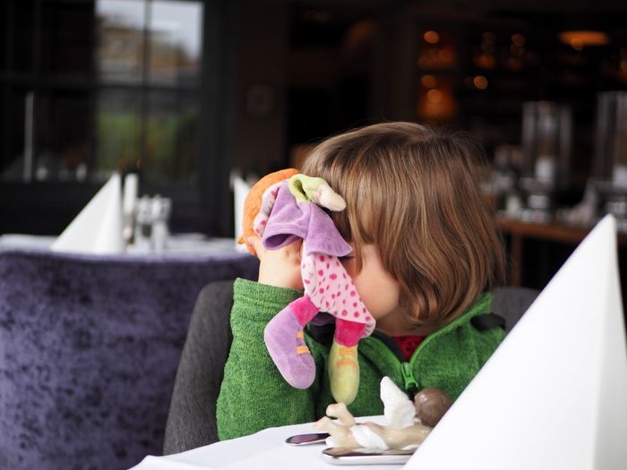 Girl holding doll at restaurant