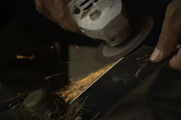 Cropped image of worker grinding steel at workshop