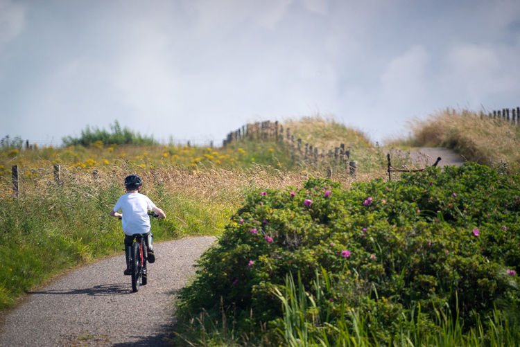 Rear view of child riding bicycle up hill