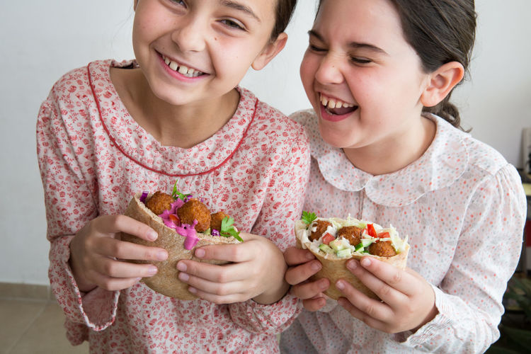 Cheerful siblings eating falafel wrap sandwich at home