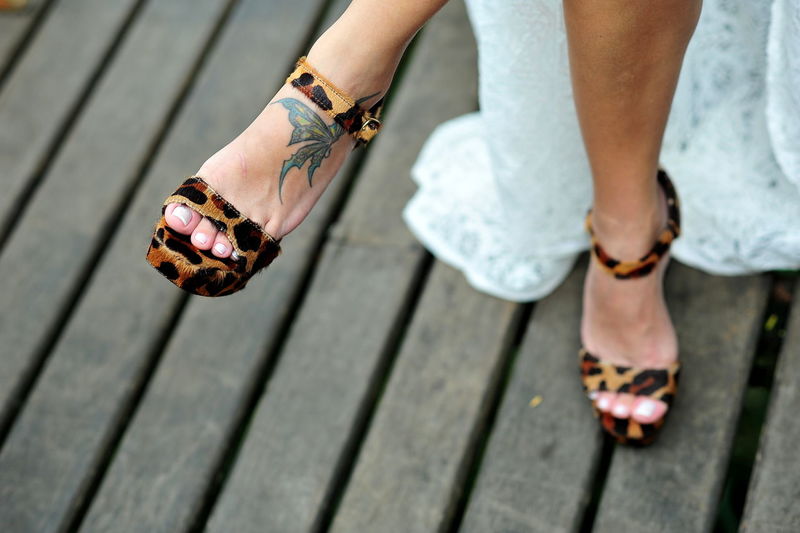 Low section of woman wearing leopard print sandals