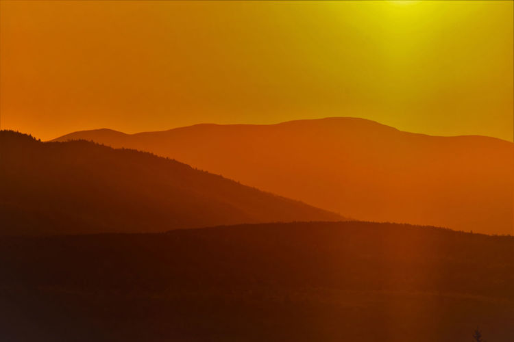 Scenic view of silhouette mountains against orange sky