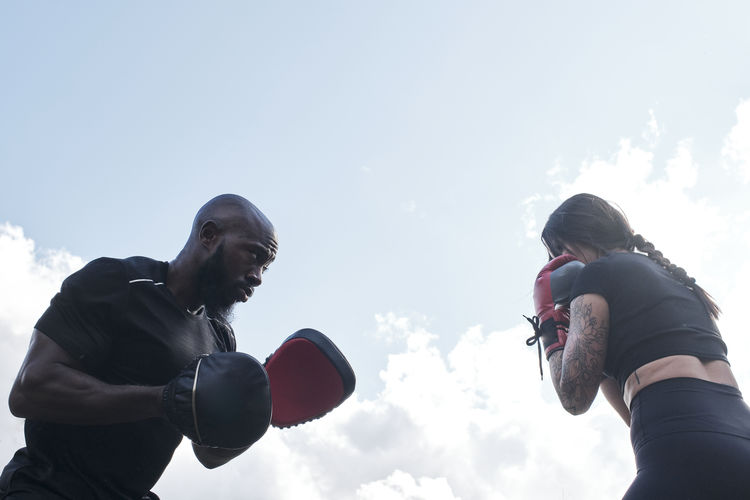 Strong brunette woman boxing outdoors with her personal coach.