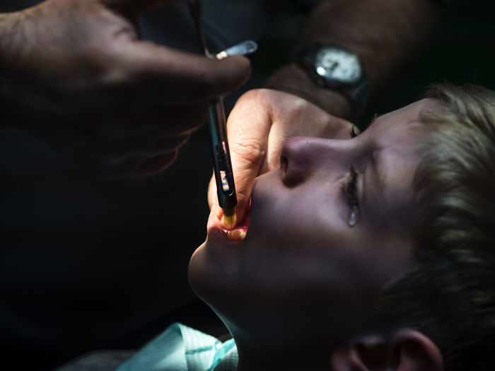 Cropped hand of dentist examining boy at hospital
