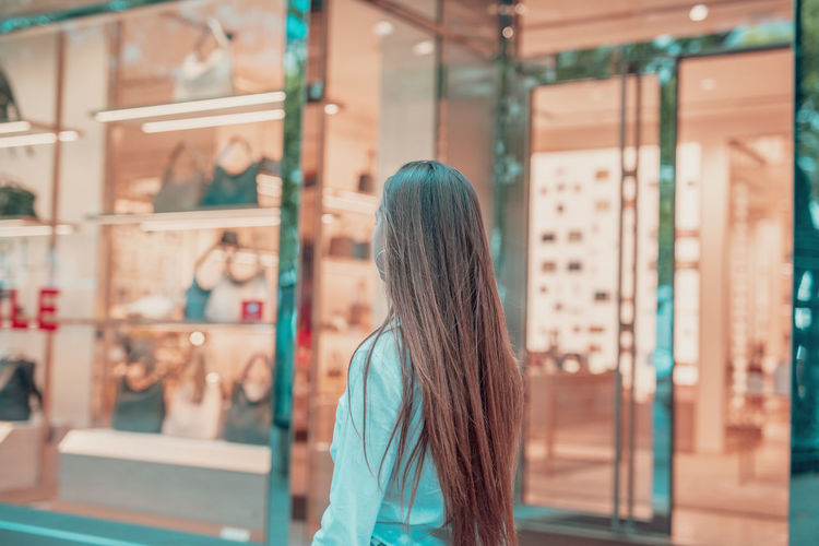 Side view of woman standing on footpath by store window