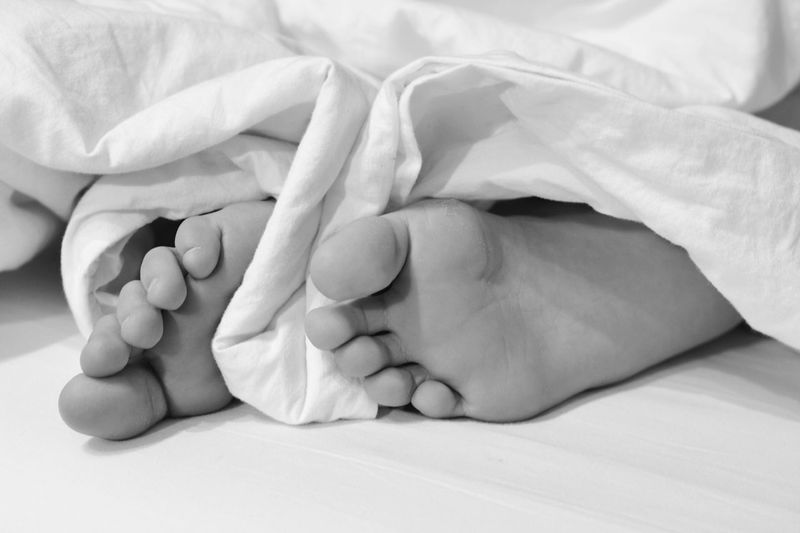 Low section of baby lying on bed