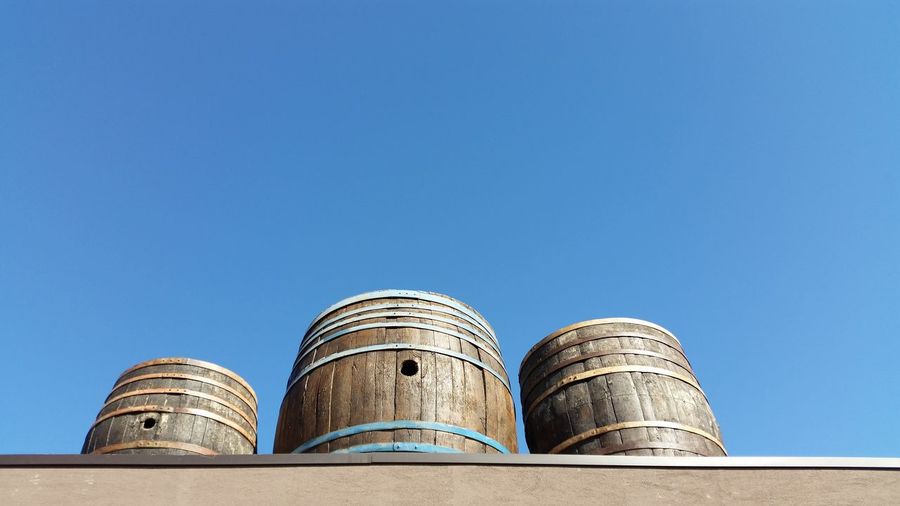 Low angle view of wooden barrels against clear sky