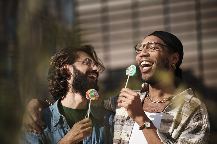 Happy gay couple eating rainbow candy