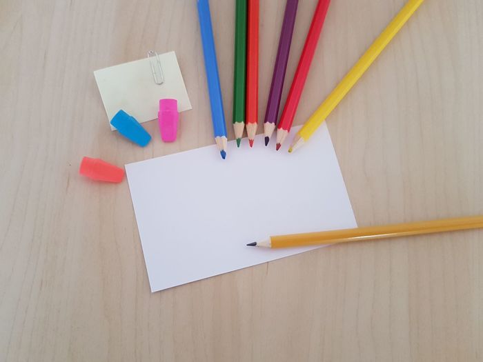 High angle view of multi colored pencils by business card on table