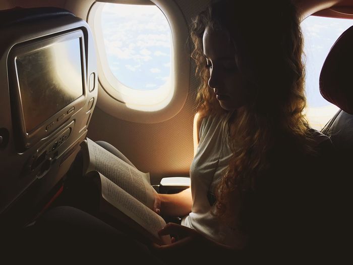 Beautiful woman reading book in airplane