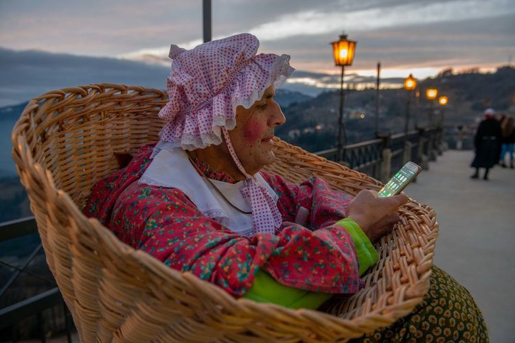 Midsection of woman sitting in basket against sky during winter