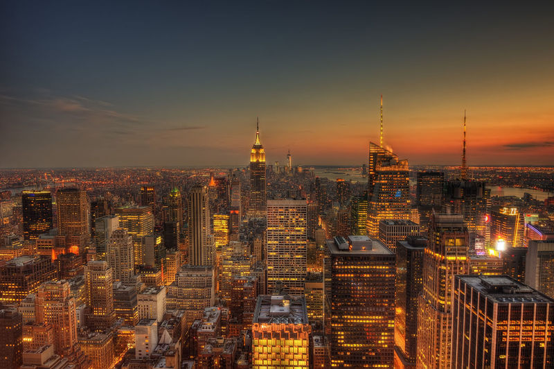 Illuminated buildings in city against sky during sunset