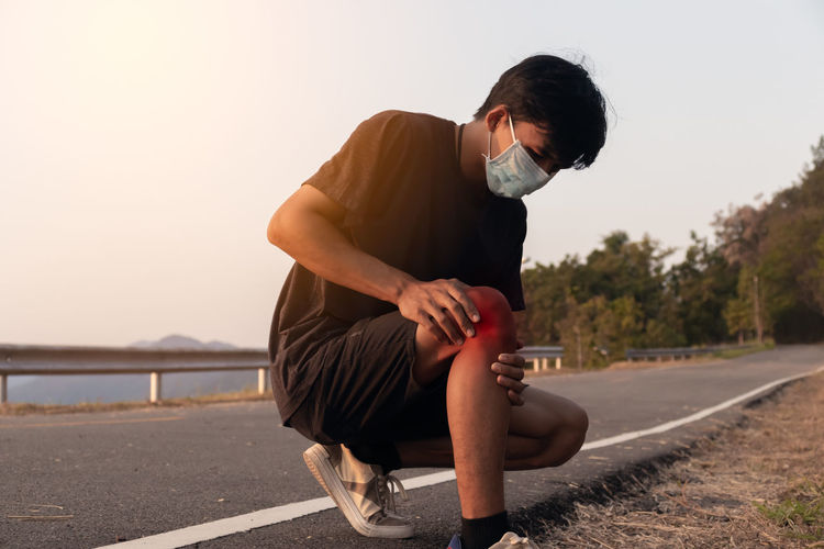 Man sitting on road against sky