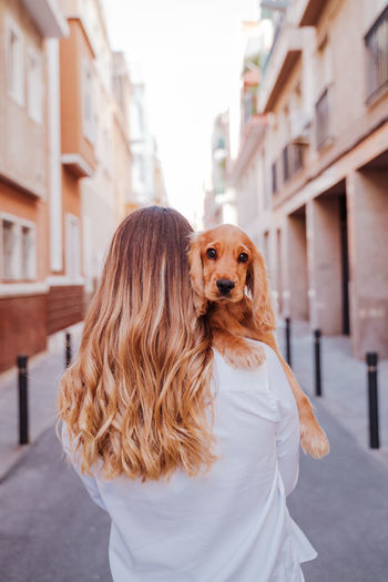 Woman carrying dog on street in city