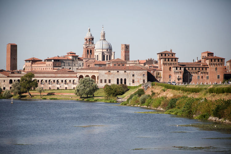 Basilica di sant andrea amidst buildings in front of river against clear sky