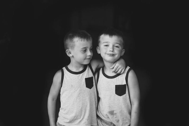 Portrait of smiling with brother standing against black background