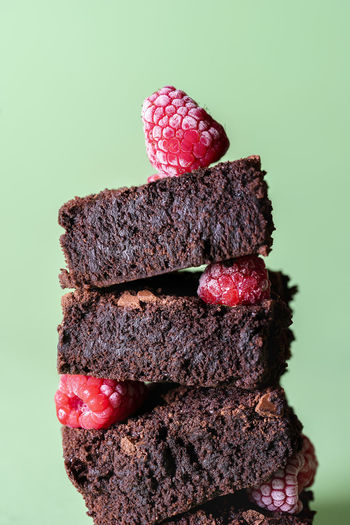Chocolate brownie close-up in a stack with frozen berries on green background. tasty cocoa cakes. 