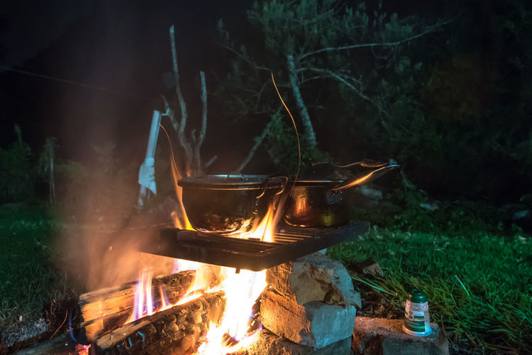 Outdoor cooking in pot over bonfire at night