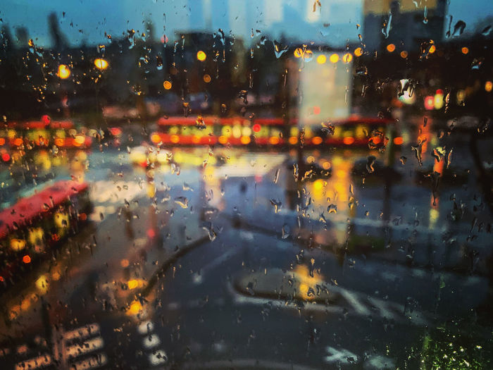 Illuminated city seen through wet glass window