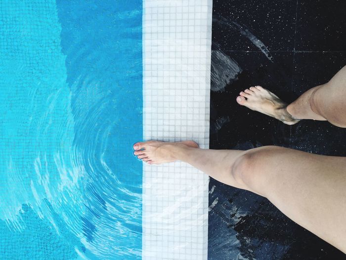 Low section of woman standing by swimming pool