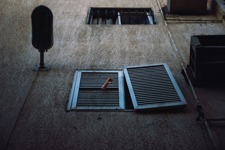 Low angle view of cropped hand at window of building