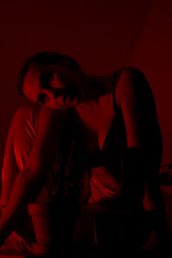 Midsection of woman sitting against red background